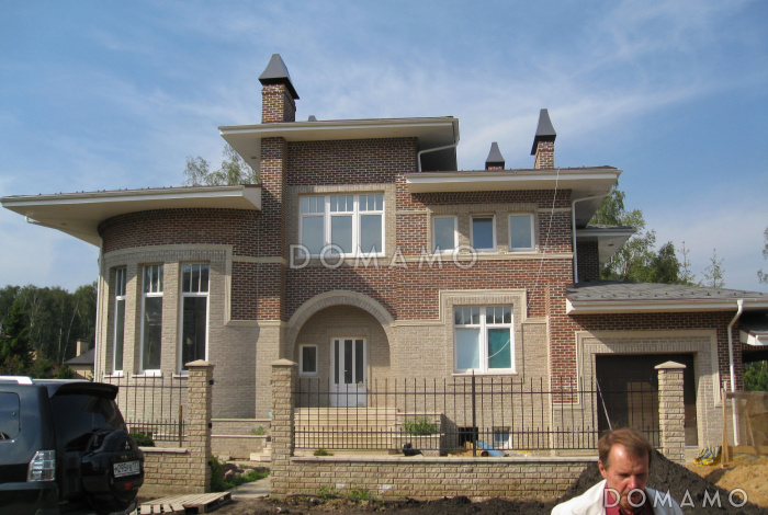 Проект коттеджа с круглой гостиной, гаражом и навесом